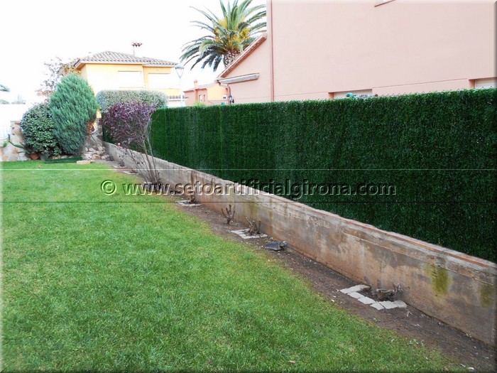 Muntatge de seto artificial girona en una tanca metàl·lica entre veïns